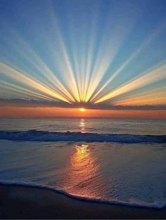 the sun is setting over the ocean with bright rays coming from it's horizon