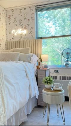 a bedroom with white bedding and floral wallpaper