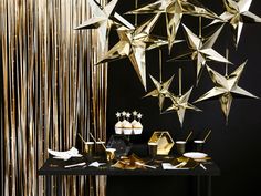 a table topped with gold stars and cupcakes next to a black counter top