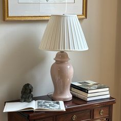 a lamp sitting on top of a wooden table next to a book and some books