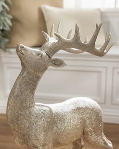 a silver statue of a deer with antlers on it's head, in front of a couch