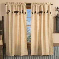 a window with curtains and stars on the curtain rod, in front of a wall