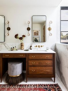 a bathroom with marble counter tops and wooden cabinets, two mirrors above the sink and a rug on the floor