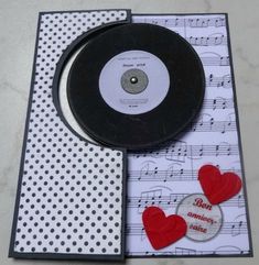 a black record with red hearts on it next to a sheet of paper and some buttons