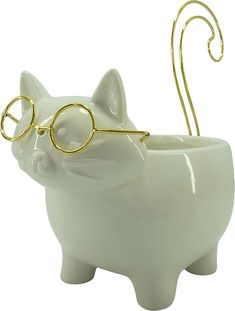 a white cat with glasses on it's head sitting in a cup shaped like a pig