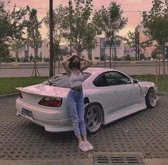 a woman leaning on the hood of a white car