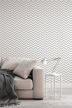 a white couch sitting in front of a wall with black and white designs on it