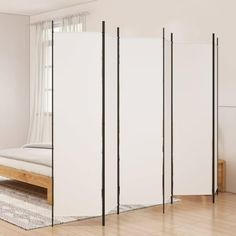 a room divider in the middle of a wooden floor with a bed and window behind it