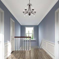 an empty room with blue walls and white trim on the stairs, chandelier and windows