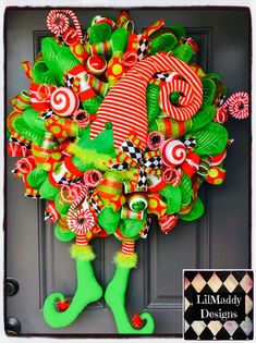 a christmas wreath with candy canes and green stockings hanging on the front door,