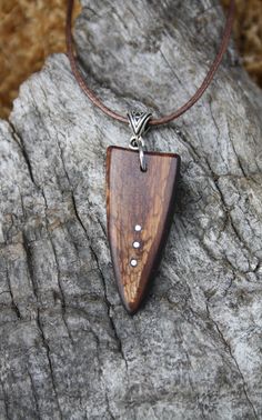 a wooden pendant is sitting on a rock