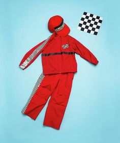 a child's red rain suit and checkered tie on a blue background with a flag