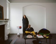 two people sitting on the floor in front of a fireplace