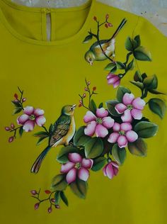 a yellow shirt with flowers and birds painted on it