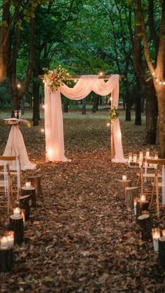 an outdoor wedding set up in the woods with candles and drapes on the ground