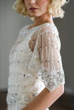 a woman with blonde hair wearing a white dress and pearls on her head, looking off to the side