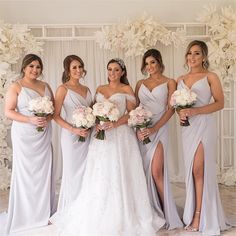 four bridesmaids pose for a photo in front of a backdrop with white flowers