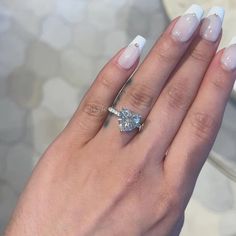 a woman's hand with white and blue manicured nails holding a diamond ring