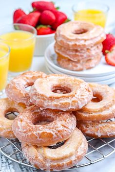 a bunch of doughnuts that are sitting on a table with strawberries and orange juice