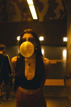 a woman blowing bubbles on her face while standing in front of a building with other people