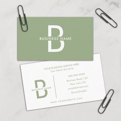 two business cards sitting on top of each other next to some clips and paper clips