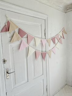 a white door with pink and beige flags hanging from it