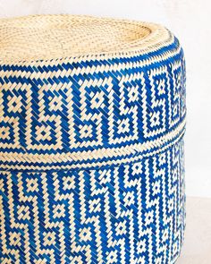 a blue and white woven basket sitting on top of a table next to a wall