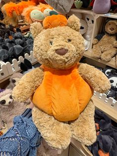 a teddy bear sitting on top of a shelf in a store filled with stuffed animals