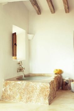 a bathroom with a large stone bathtub next to a sink and mirror on the wall