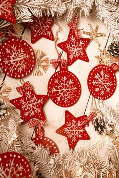 some red and white ornaments are hanging on a christmas tree with snowflakes