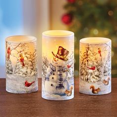 three frosted glass mugs sitting on top of a wooden table next to a christmas tree