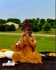 a woman sitting on the ground taking a photo with her cell phone while wearing an orange dress