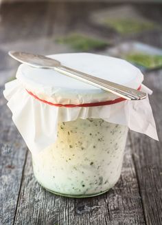 a jar filled with food sitting on top of a wooden table next to a spoon