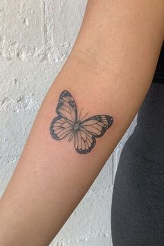 a woman's arm with a butterfly tattoo on the left side of her arm