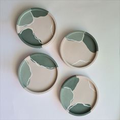 three green and white plates sitting on top of a table next to each other with leaves painted on them