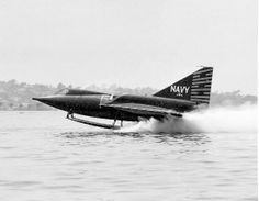 an old navy plane is flying low over the water with its landing gear on it's side