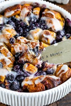 a blueberry cobbler is shown in a white dish with a serving spatula