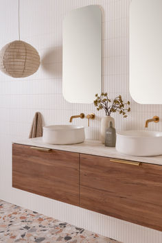 two white sinks sitting on top of a wooden cabinet next to a wall mounted mirror