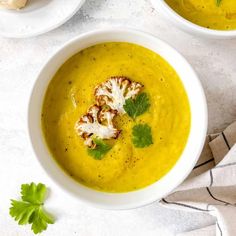 two bowls of soup with cauliflower garnish and parsley on the side