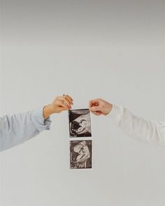 two people reaching out their hands to each other with pictures hanging from the ceiling above them