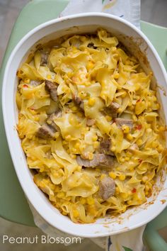 a casserole dish with meat and noodles in it on a green tablecloth