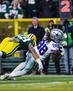 a football player diving for the ball while being tackled by another player