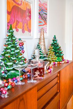 there are many christmas trees on the counter in this room, and one is decorated with ornaments