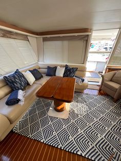 a living room filled with furniture and pillows on top of a wooden floor next to a window