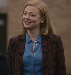 a woman in a blue shirt and jacket talking to another woman wearing a black blazer