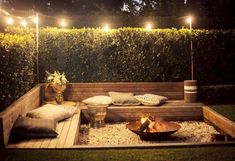 an outdoor fire pit is lit up by string lights