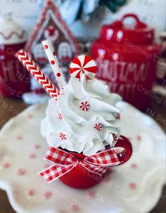 a cup filled with whipped cream and candy canes on top of a white plate