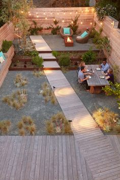 two people sitting at a table in a small backyard with an outdoor fire pit and seating area