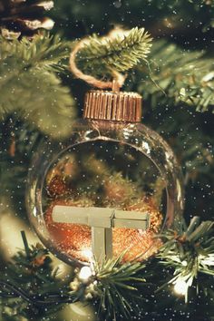 an ornament hanging from a christmas tree with the letter t in it's center