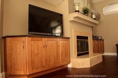 a flat screen tv sitting on top of a wooden cabinet next to a fire place